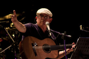 Silvio Rodríguez en un concierto, con guitarra y micrófono, expresando sus opiniones.