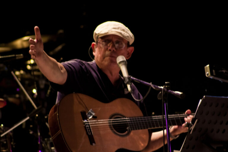 Silvio Rodríguez en un concierto, con guitarra y micrófono, expresando sus opiniones.