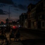 Vista nocturna de La Habana con personas sentadas en la acera