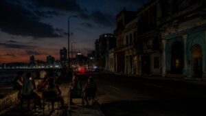 Vista nocturna de La Habana con personas sentadas en la acera