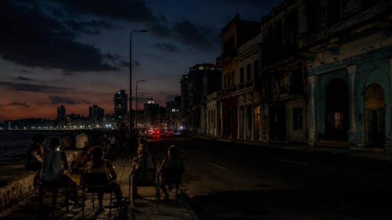 Vista nocturna de La Habana con personas sentadas en la acera